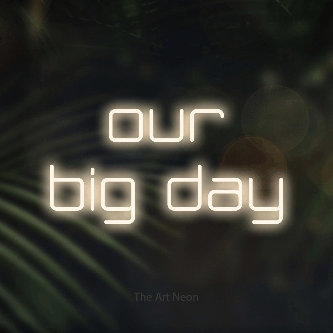 Warm white LED neon sign reading "Our Big Day" against dark blurred palm leaves for wedding décor