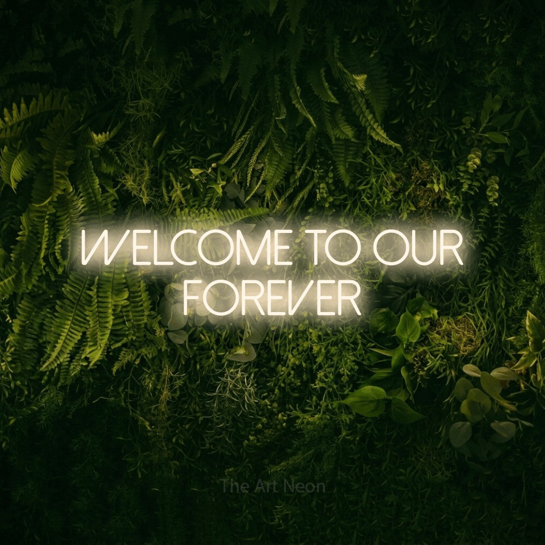 Warm white LED neon sign reading "Welcome to Our Forever" against a moss-covered green wall for wedding décor