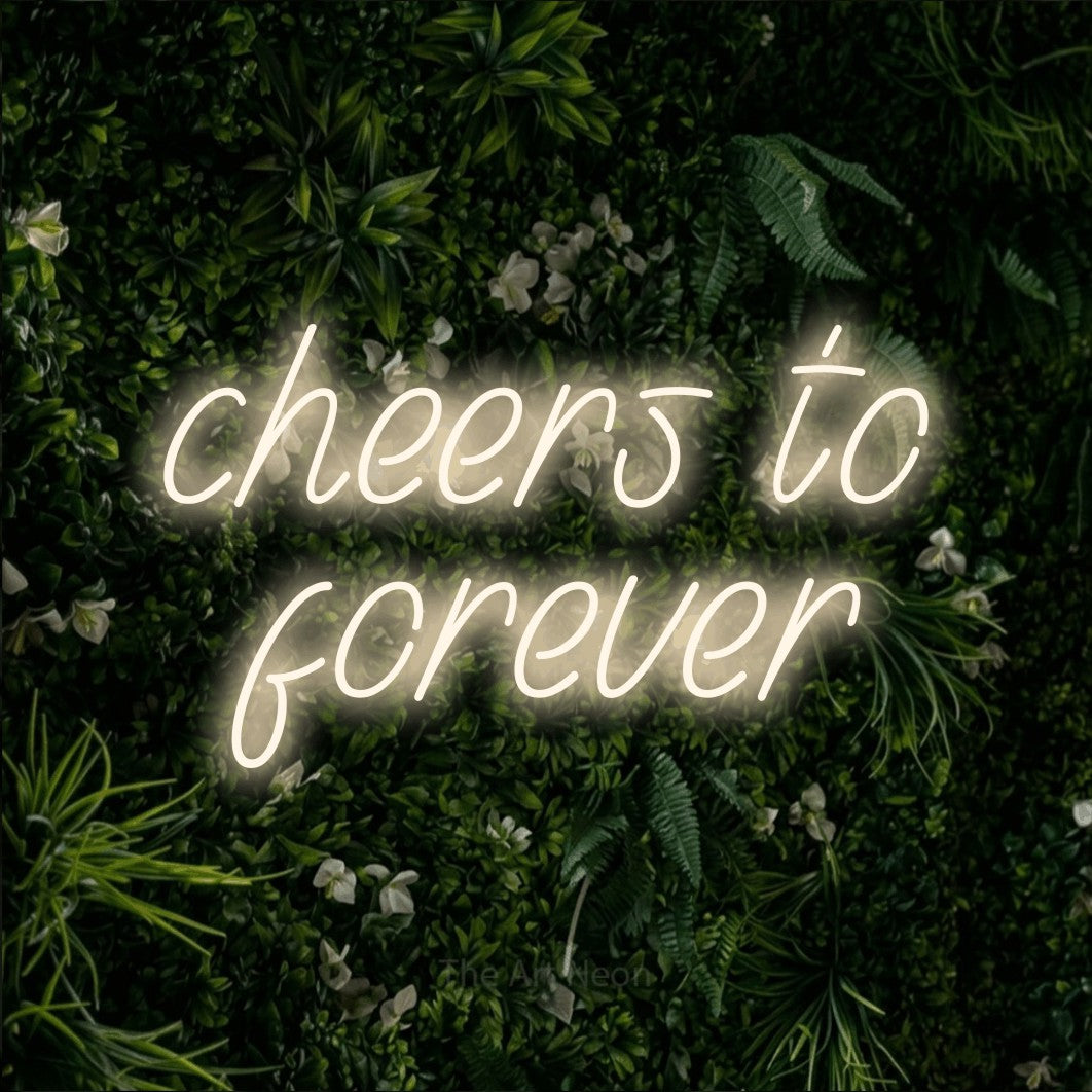 Enseigne néon à DEL à lumière blanche chaude, affichant « Cheers to Forever » sur un mur de feuillage vert, pour décorer un mariage