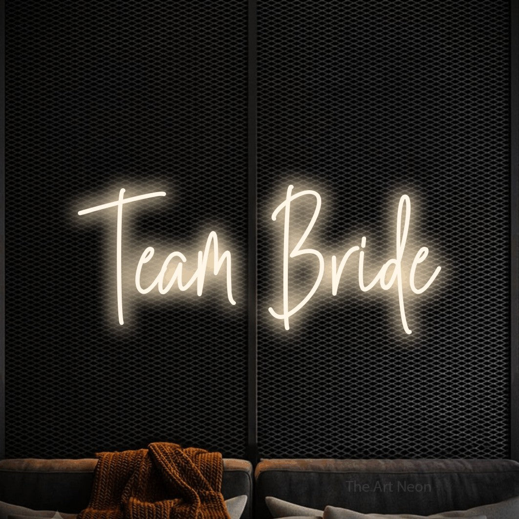 Warm white script-style LED neon sign reading "Team Bride" against a black textured wall for wedding décor
