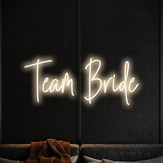 Warm white script-style LED neon sign reading "Team Bride" against a black textured wall for wedding décor