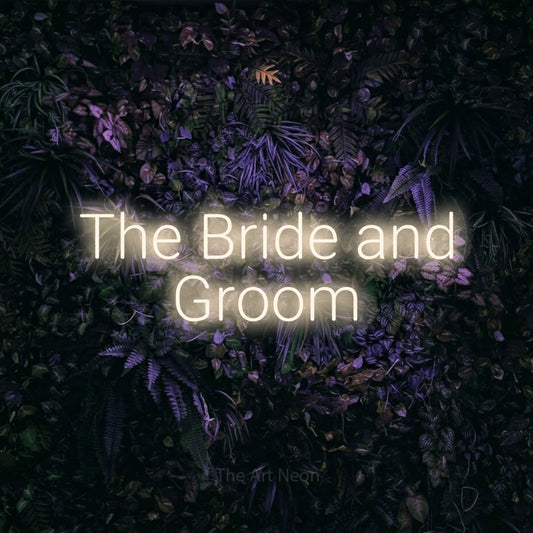 Warm white LED neon sign reading "The Bride and Groom" against a purple floral wall for wedding décor