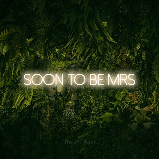 Warm white LED neon sign reading "Soon to Be Mrs" against a moss-covered green wall for wedding décor