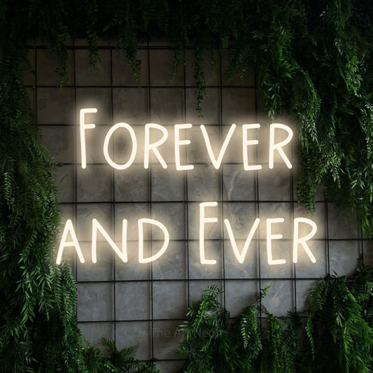Warm white LED neon sign reading "Forever and Ever" against a green grid wall with foliage for wedding décor
