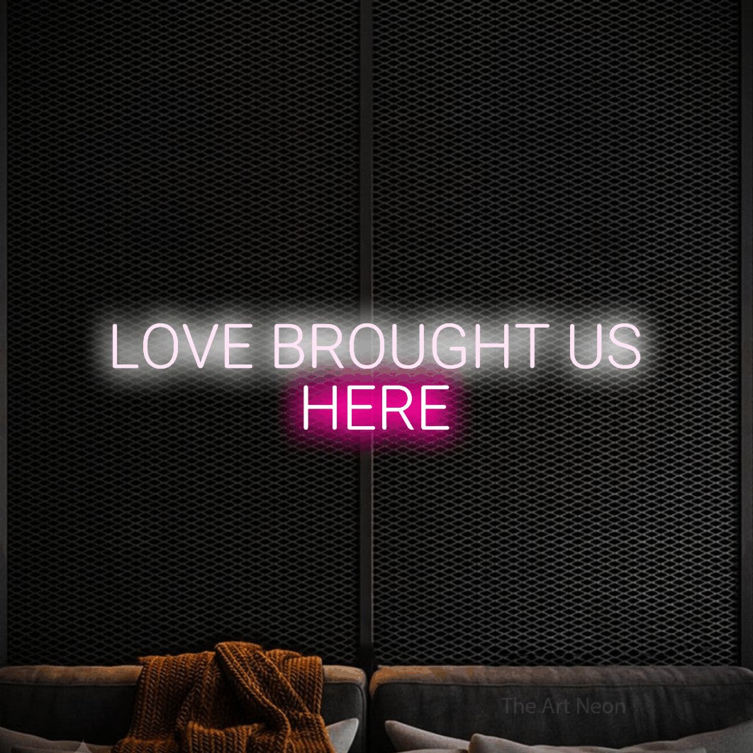Hot pink and cool white LED neon sign reading "Love Brought Us Here" against a black textured wall for wedding décor