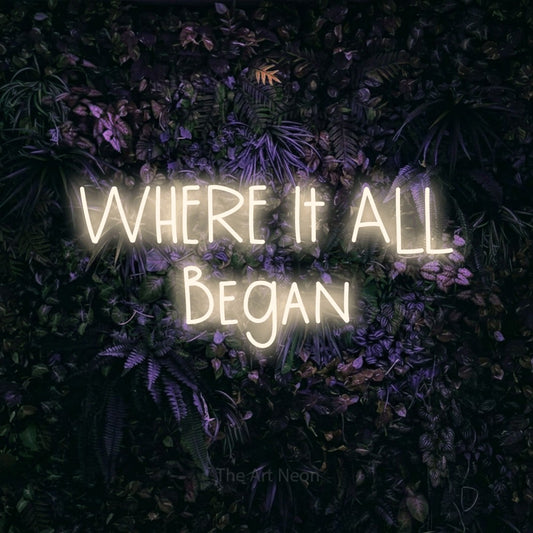 Warm white LED neon sign reading "Where It All Began" against a purple floral wall for wedding décor