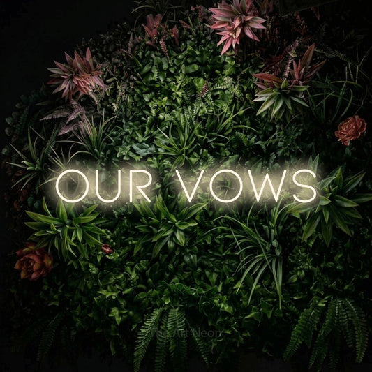 Warm white LED neon sign reading "Our Vows" against a flowering garden wall for wedding décor