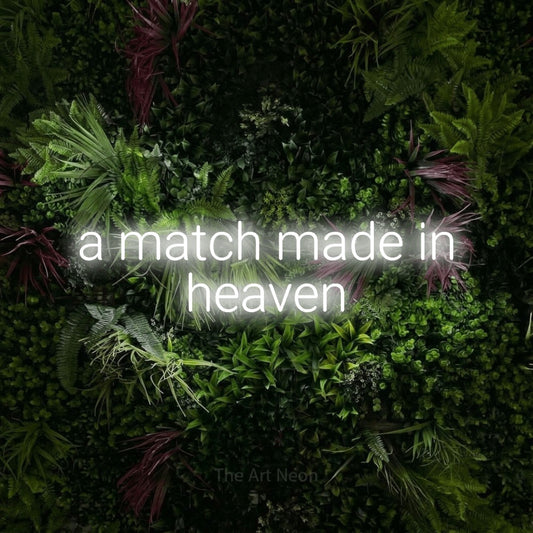 Cool white LED neon sign reading "A Match Made in Heaven" against a lush garden wall with pink flowers for wedding décor