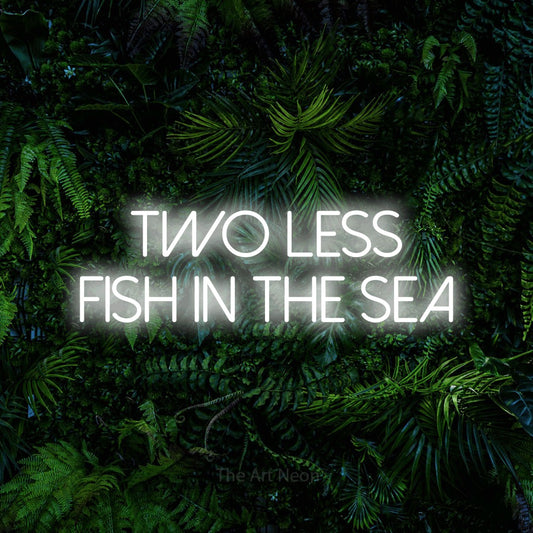 Cool white LED neon sign reading "Two Less Fish in the Sea" against a dense tropical foliage wall for wedding décor