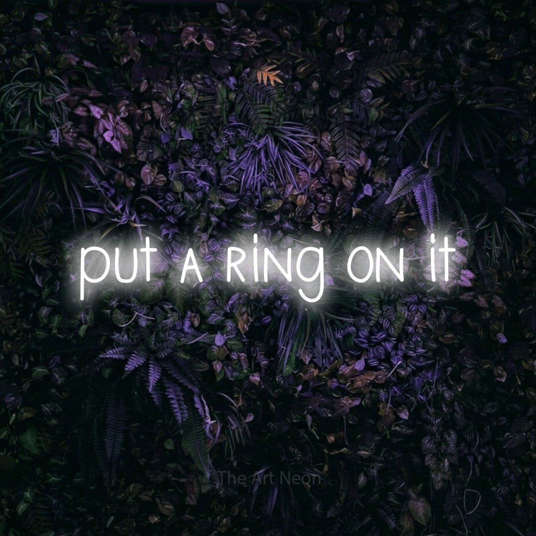 Cool white LED neon sign reading "Put a Ring on It" against a purple floral wall for wedding décor