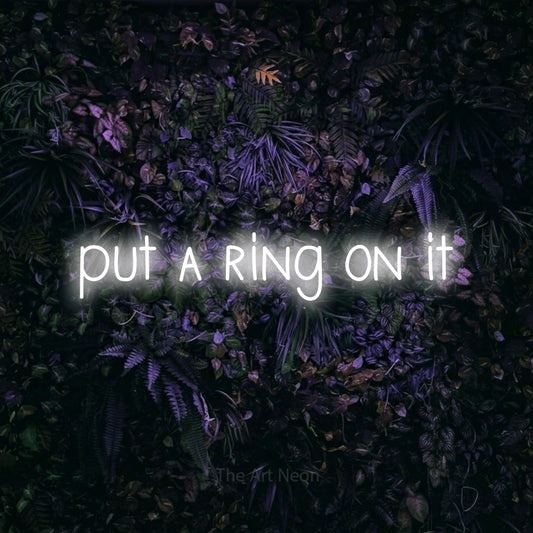 Cool white LED neon sign reading "Put a Ring on It" against a purple floral wall for wedding décor