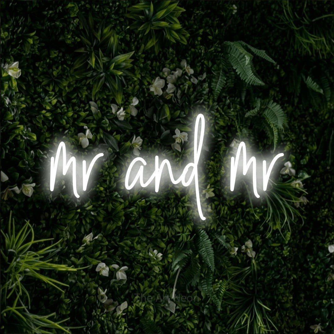Cool white script-style LED neon sign reading "Mr and Mr" against a leafy green wall for wedding décor
