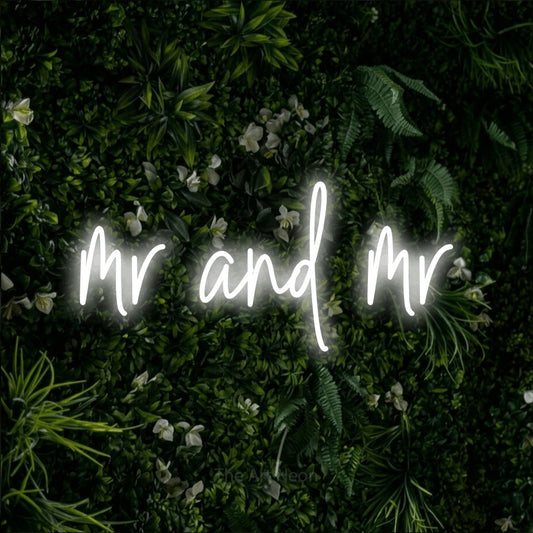 Cool white script-style LED neon sign reading "Mr and Mr" against a leafy green wall for wedding décor