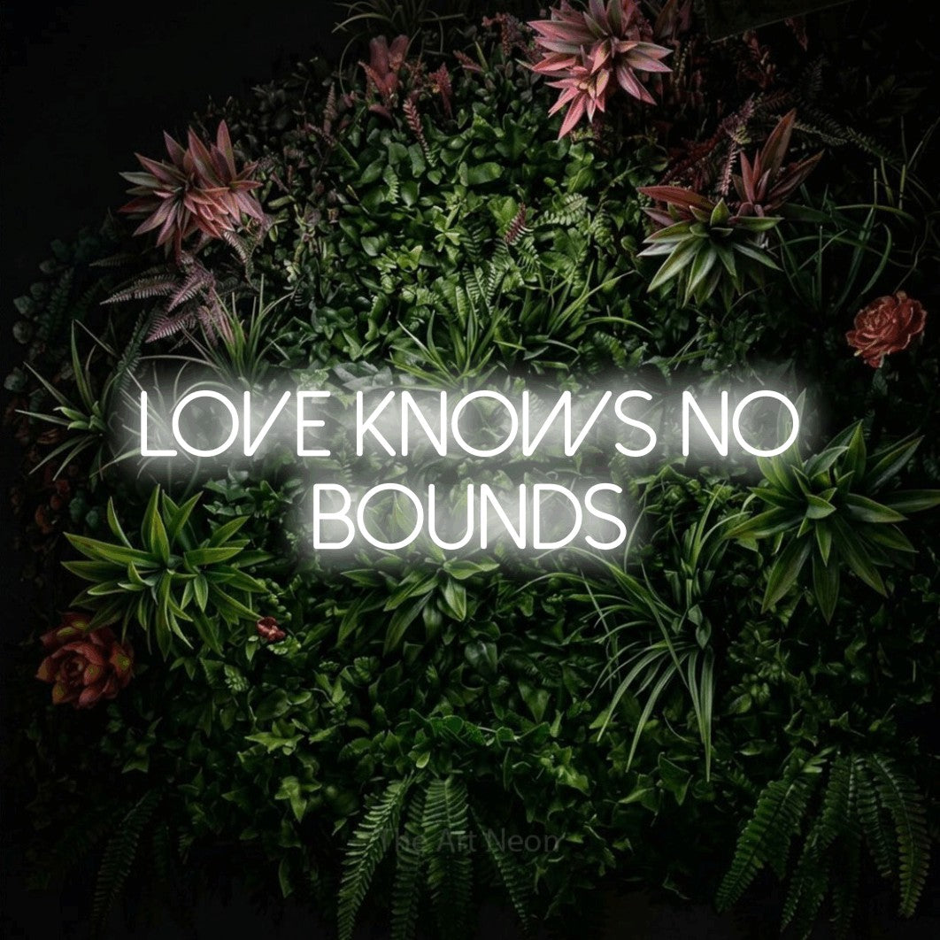 Cool white LED neon sign reading "Love Knows No Bounds" against a flowering garden wall for wedding décor