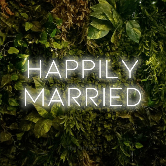 Cool white LED neon sign reading "Happily Married" against a textured moss and foliage wall for wedding décor