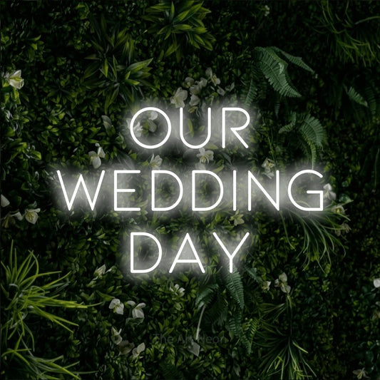 Cool white LED neon sign reading "Our Wedding Day" against a leafy green wall for wedding décor