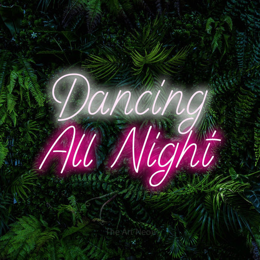 Hot pink and cool white LED neon sign reading "Dancing All Night" against a dense tropical foliage wall for wedding décor