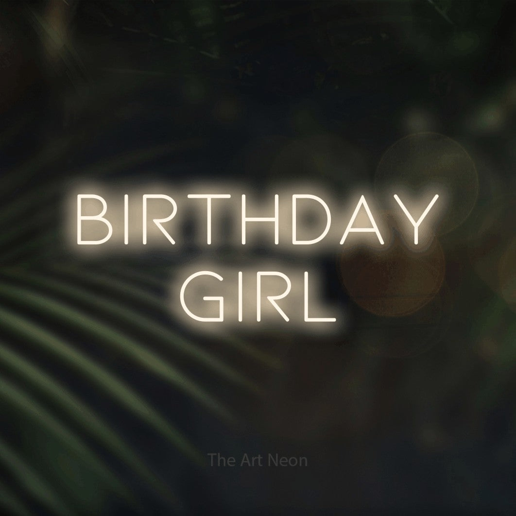 Warm white LED neon sign reading "Birthday Girl" against dark blurred palm leaves for party décor