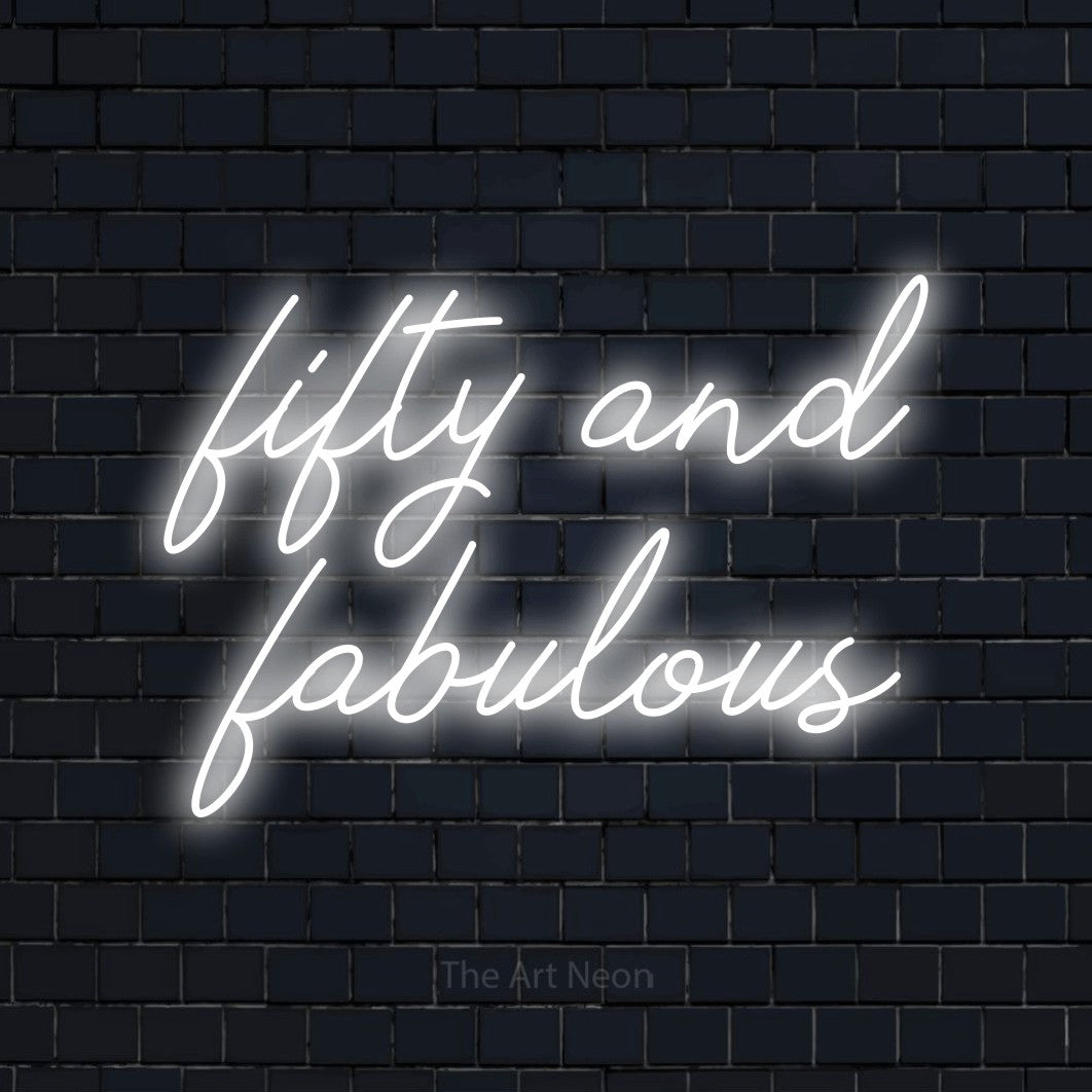 Cool white script-style LED neon sign reading "Fifty and Fabulous" against a dark navy brick wall for party décor