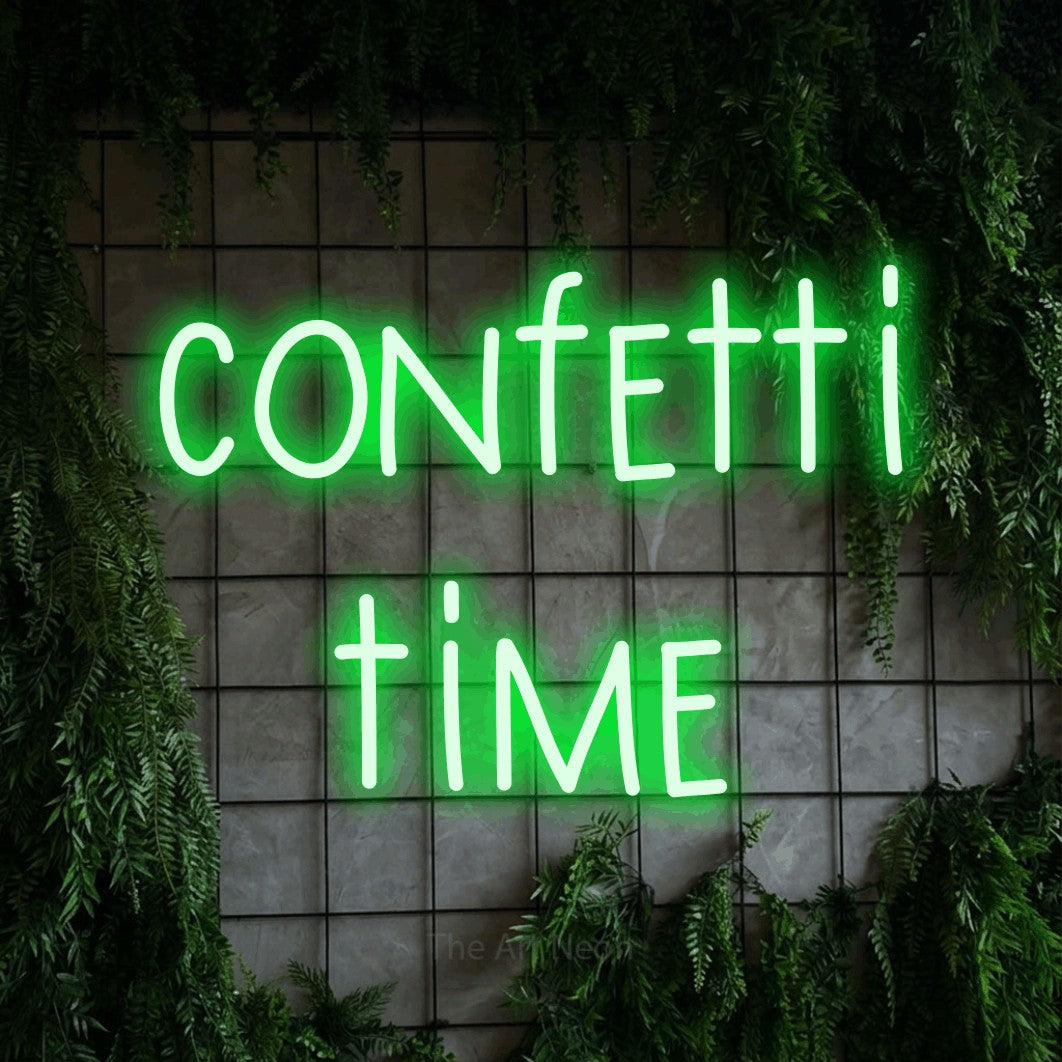 Green LED neon sign reading "Confetti Time" against a green grid wall with foliage for party décor