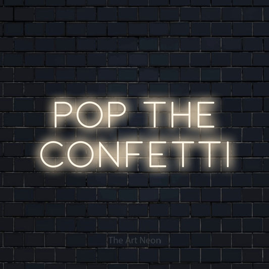 Warm white LED neon sign reading "Pop the Confetti" against a dark navy brick wall for party décor