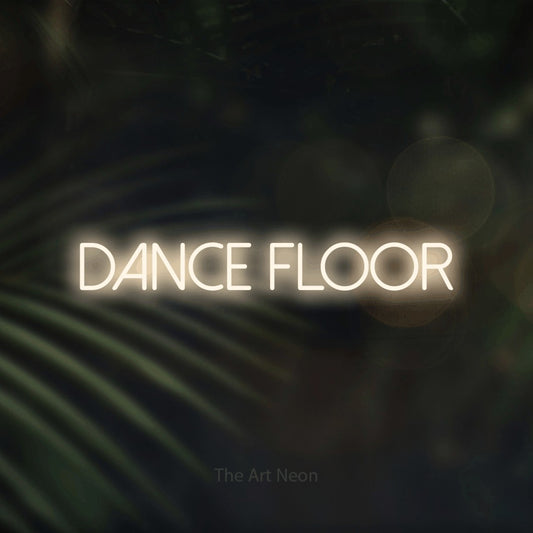 Warm white LED neon sign reading "Dance Floor" against dark blurred palm leaves for party décor