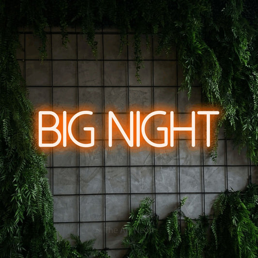 Orange LED neon sign reading "Big Night" against a green grid wall with foliage for party décor