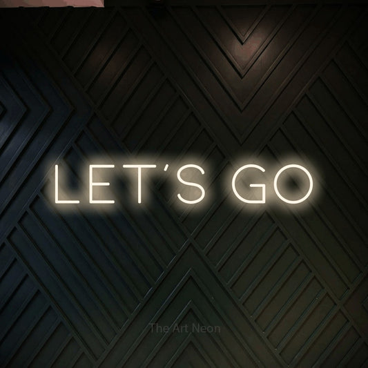Warm white LED neon sign reading "Let's Go" against a dark geometric wood wall for party décor