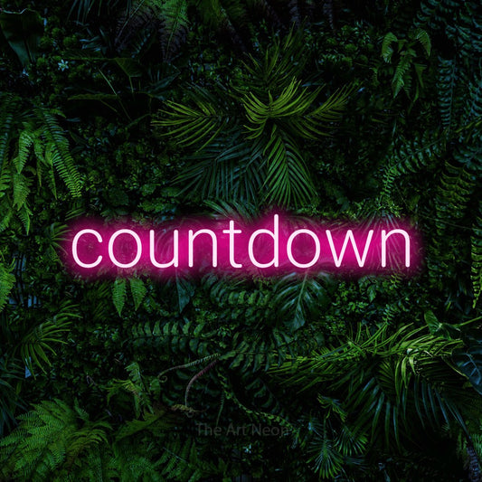 Hot pink LED neon sign reading "Countdown" against a dense tropical foliage wall for party décor