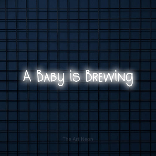 Cool white LED neon sign reading "A Baby is Brewing" against a dark blue tiled wall