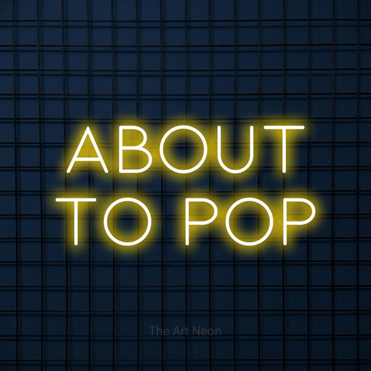 Yellow LED neon sign reading "About to Pop" against a dark blue tiled wall
