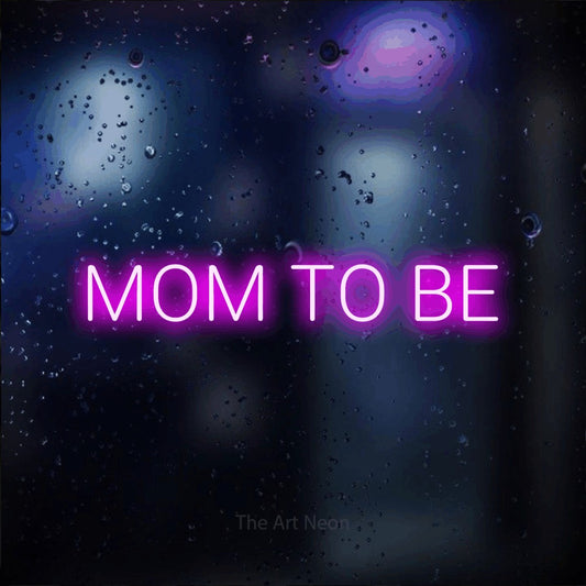 Enseigne néon à DEL à lumière rose, affichant « Mom to Be » sur un arrière-plan bokeh bleu foncé