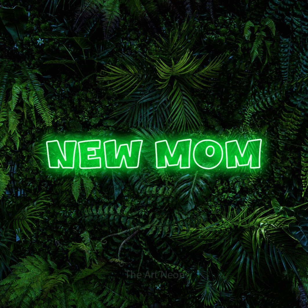 Green outline-style LED neon sign reading "New Mom" against a dense tropical foliage wall