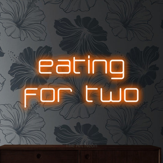 Enseigne néon à DEL à lumière orange, affichant « Eating for Two » sur un papier peint floral gris