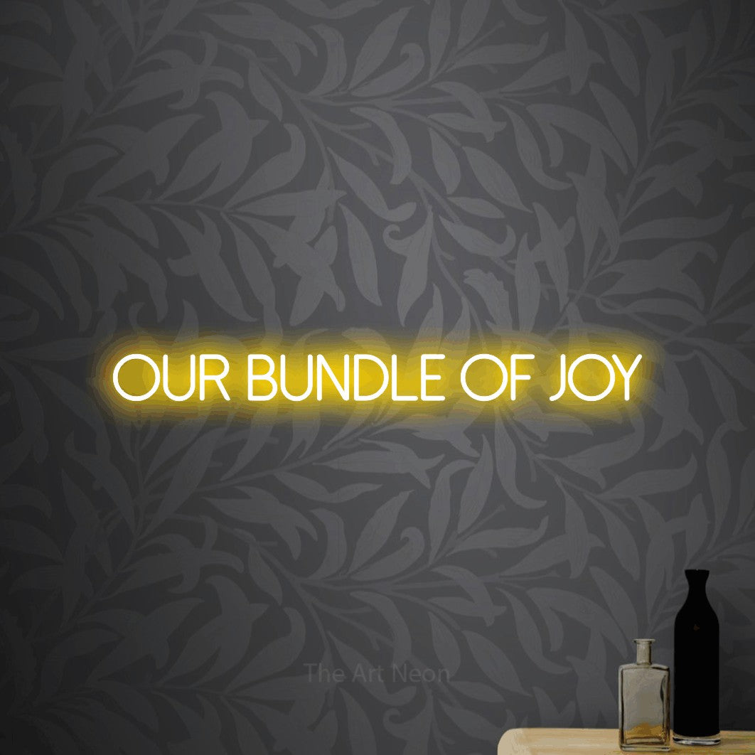 Enseigne néon à DEL à lumière jaune, affichant « Our Bundle of Joy » sur un papier peint floral gris pâle