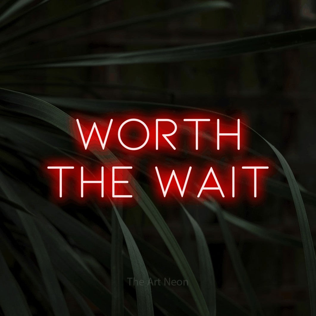 Red LED neon sign reading "Worth the Wait" against dark tropical leaves