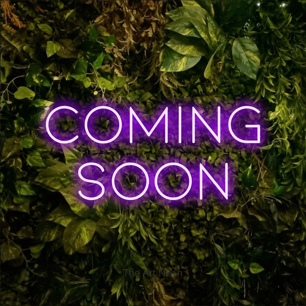 Purple LED neon sign reading "Coming Soon" against a textured moss and foliage wall