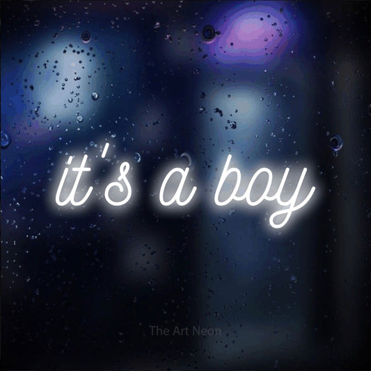 Cool white script-style LED neon sign reading "It's a Boy" against a dark blue bokeh background