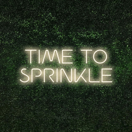 Warm white LED neon sign reading "Time to Sprinkle" against a textured green moss wall