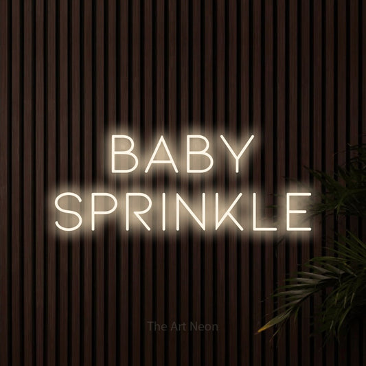 Warm white LED neon sign reading "Baby Sprinkle" against dark wooden slats
