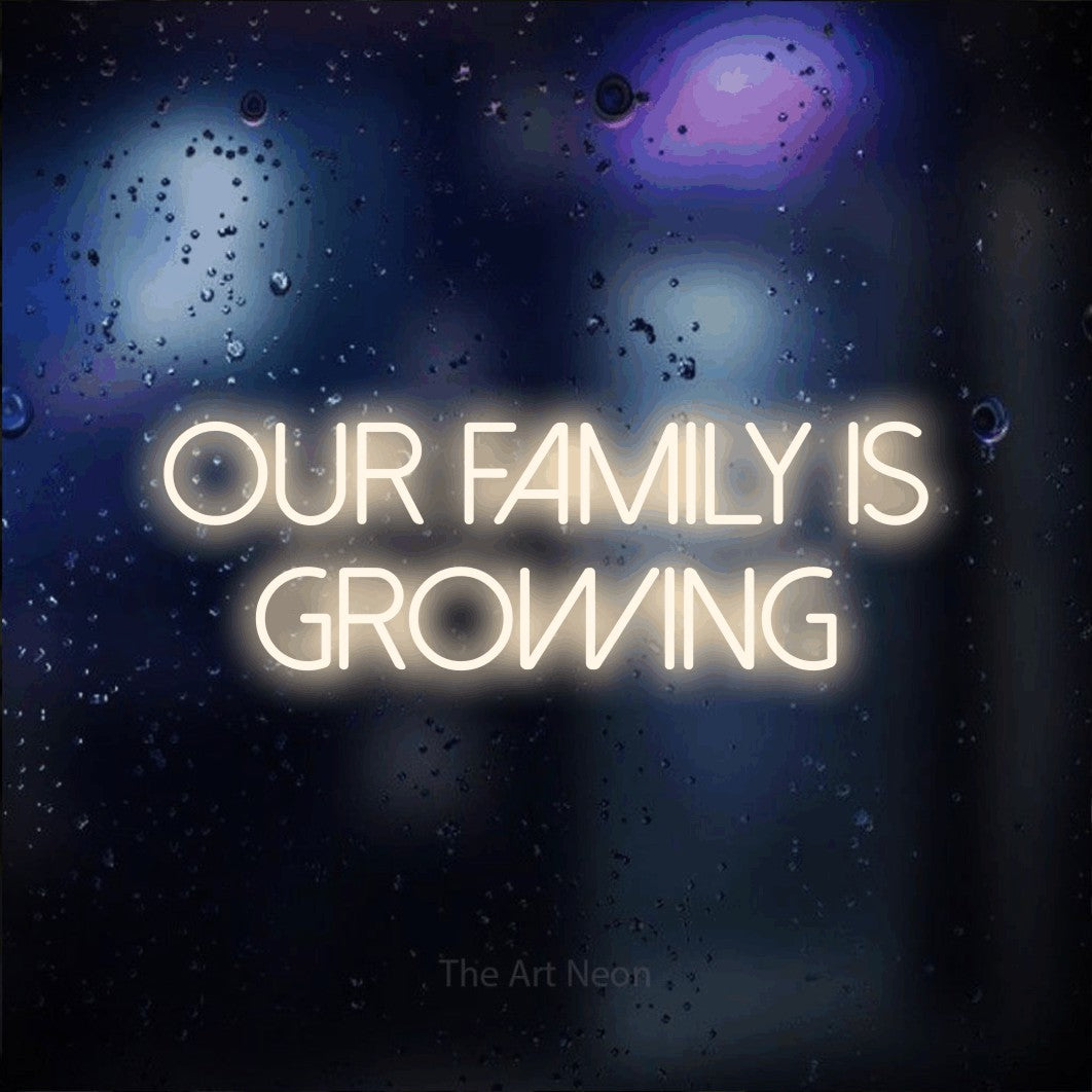 Enseigne néon à DEL à lumière blanche chaude, affichant « Our Family is Growing » sur un arrière-plan bokeh bleu foncé