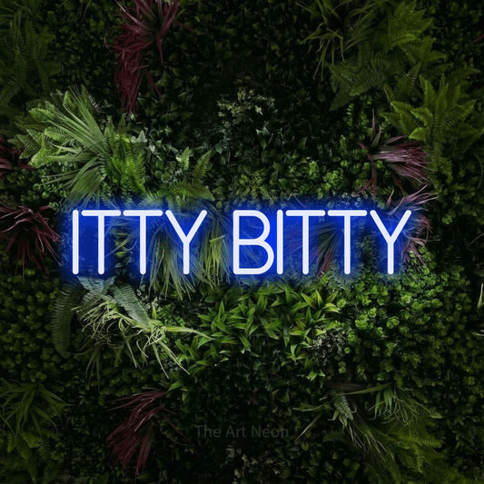 Blue LED neon sign reading "Itty Bitty" against a lush garden wall with pink flowers