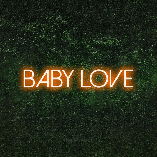 Orange LED neon sign reading "Baby Love" against a textured green moss wall