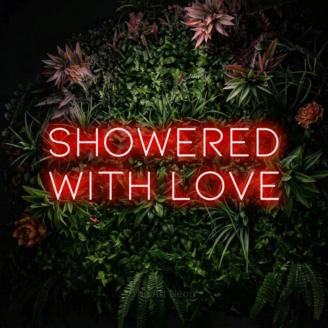 Enseigne néon à DEL à lumière rouge, affichant « Showered with Love » sur un mur de jardin fleuri