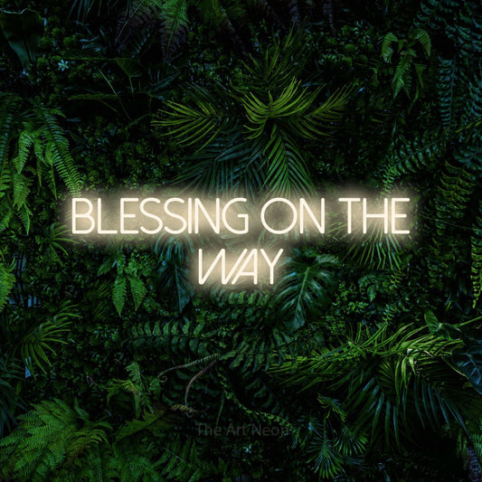 Warm white LED neon sign reading "Blessing on the Way" against a dense tropical foliage wall