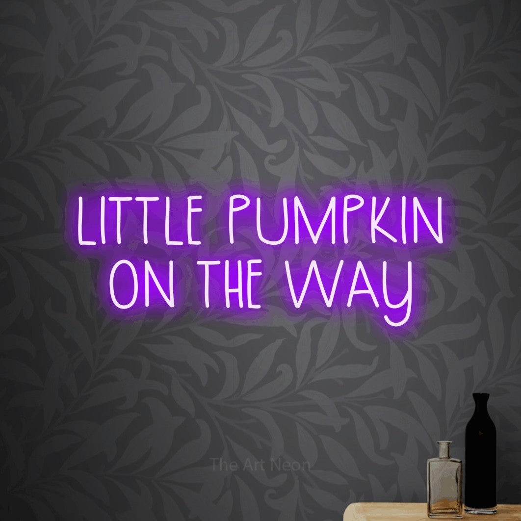 Purple LED neon sign reading "Little Pumpkin on the Way" against light grey floral wallpaper