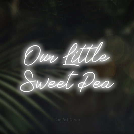 Cool white script-style LED neon sign reading "Our Little Sweet Pea" against dark blurred palm leaves