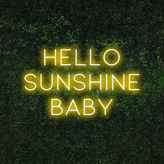 Yellow LED neon sign reading "Hello Sunshine Baby" against a textured green moss wall