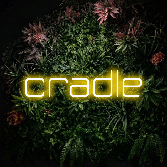 Yellow LED neon sign reading "Cradle" against a flowering garden wall
