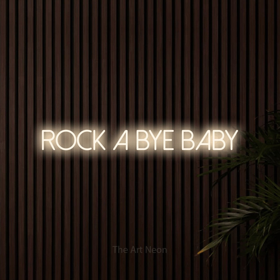 Warm white LED neon sign reading "Rock a Bye Baby" against dark wooden slats
